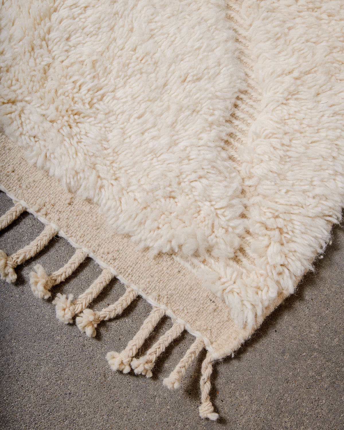 Corner of cream Beniourain rug with natural wool tassels.